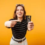Excited girl pointing finger at a credit card - Travel Rewards Credit Cards concept